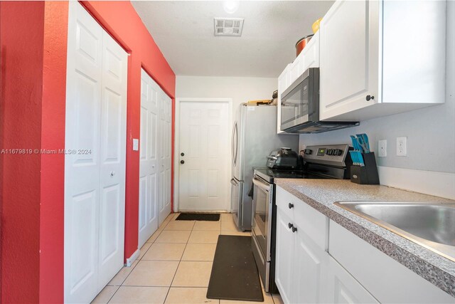 kitchen featuring appliances with stainless steel finishes, white cabinetry, and light tile patterned flooring