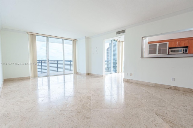 spare room featuring expansive windows, crown molding, and plenty of natural light