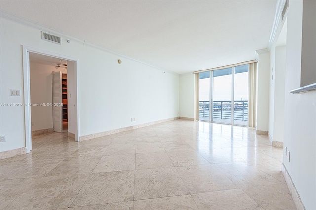 unfurnished room with ornamental molding and expansive windows