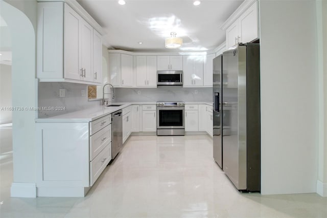 kitchen with backsplash, white cabinetry, sink, and stainless steel appliances