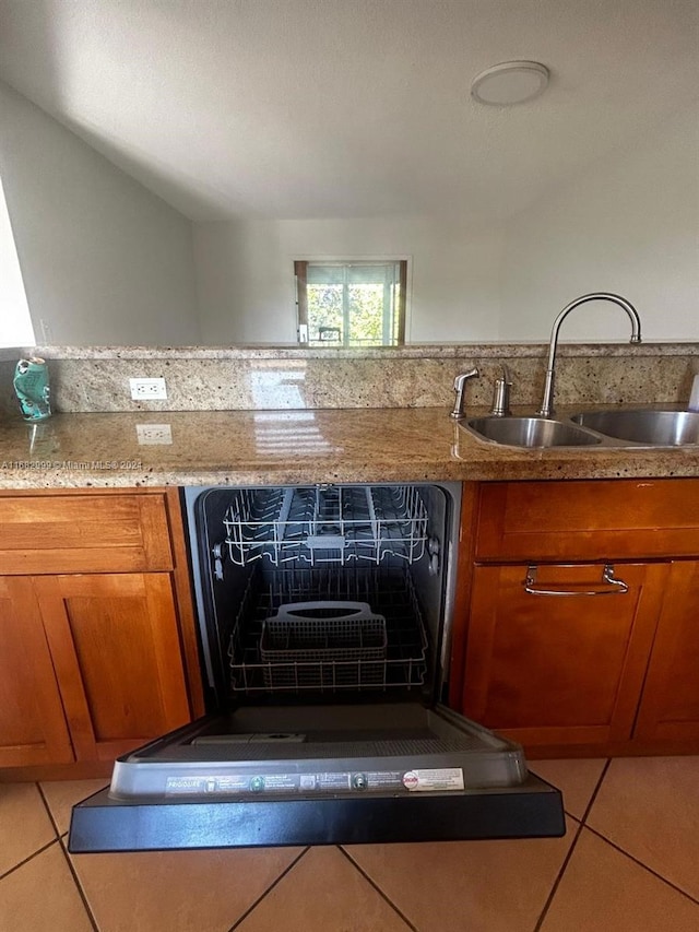 kitchen with dishwashing machine, light tile patterned flooring, light stone counters, and sink