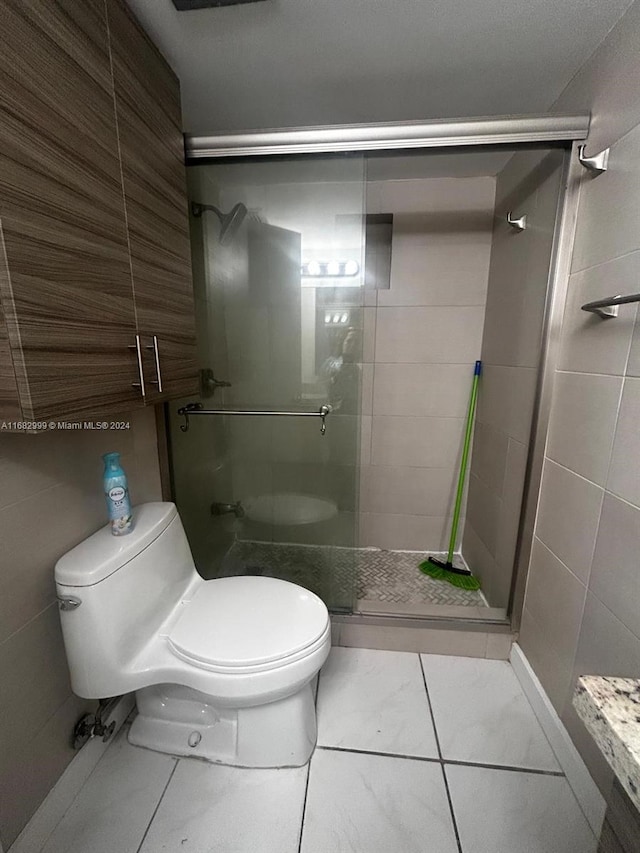 bathroom featuring tile walls, tile patterned flooring, an enclosed shower, and toilet