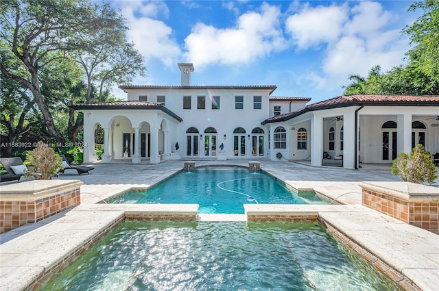 back of property featuring a swimming pool with hot tub and a patio area