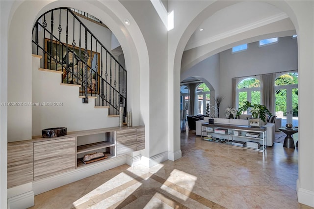 foyer entrance featuring french doors, crown molding, tile patterned floors, and a high ceiling