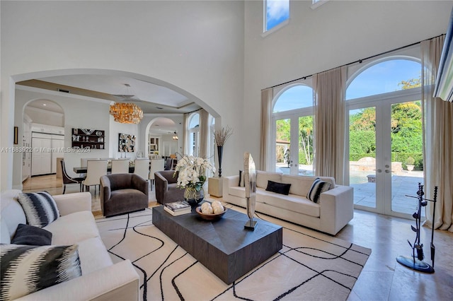 living room with french doors, a towering ceiling, and an inviting chandelier