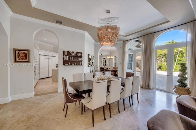 dining area with an inviting chandelier, french doors, a tray ceiling, and crown molding