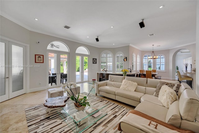 living room featuring french doors, a notable chandelier, and crown molding