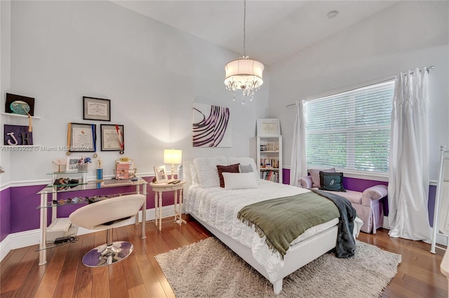 bedroom featuring high vaulted ceiling, a notable chandelier, and wood-type flooring