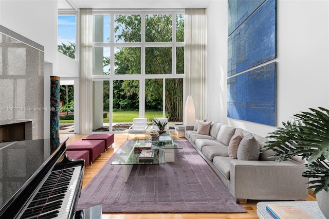 living room with a towering ceiling, expansive windows, a tile fireplace, and hardwood / wood-style floors