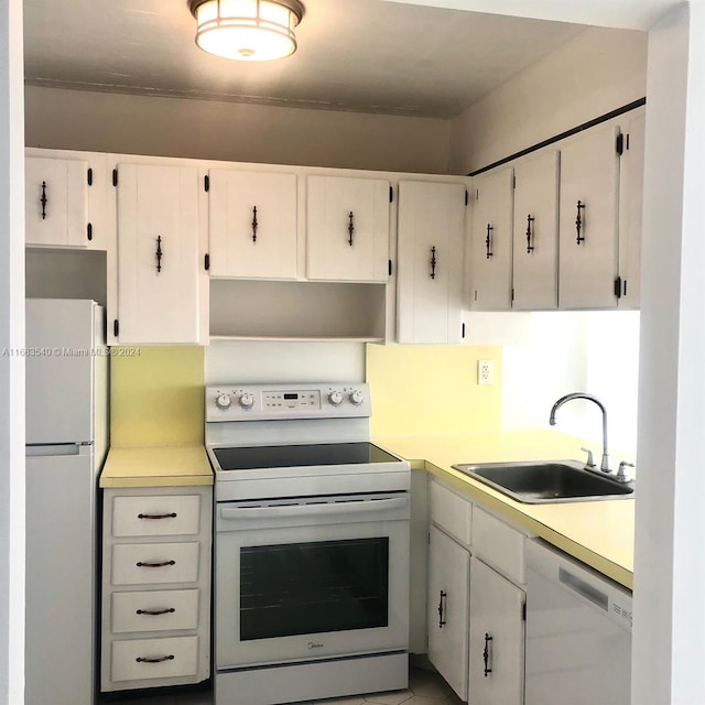 kitchen featuring sink, white cabinets, and white appliances