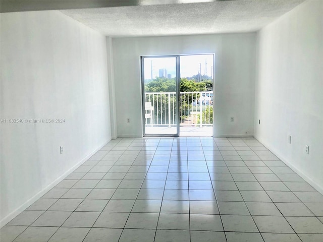 empty room featuring a textured ceiling and light tile patterned floors