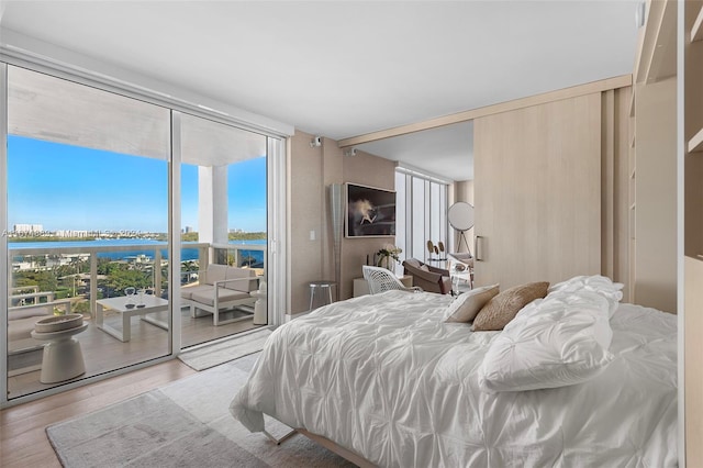 bedroom featuring a water view, light hardwood / wood-style floors, and floor to ceiling windows