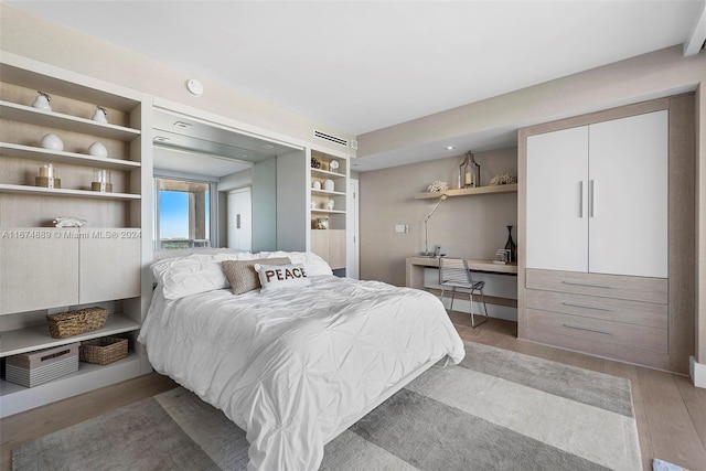 bedroom featuring built in desk and light hardwood / wood-style floors