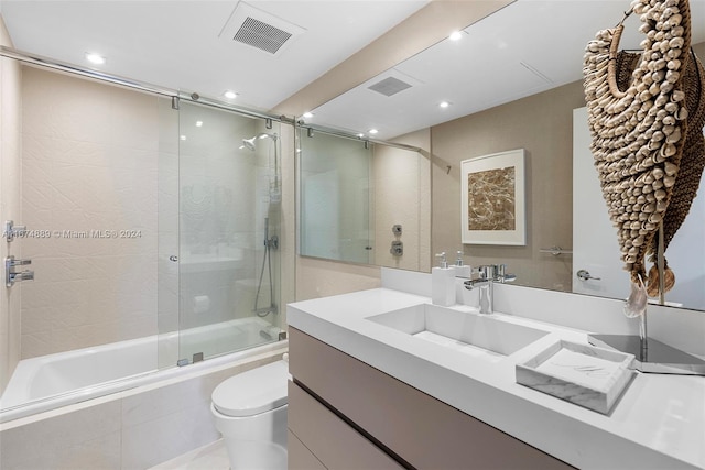 full bathroom with bath / shower combo with glass door, toilet, and vanity