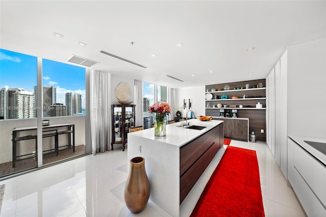 kitchen featuring white cabinetry, sink, a center island with sink, and light tile patterned floors