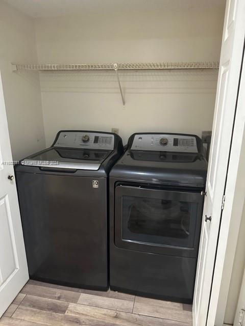 laundry room with washing machine and dryer and light hardwood / wood-style floors