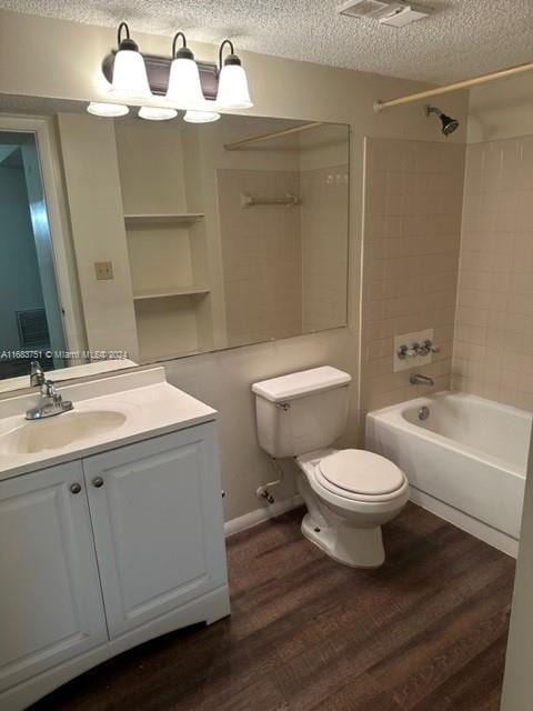 full bathroom featuring toilet, wood-type flooring, tiled shower / bath combo, vanity, and a textured ceiling