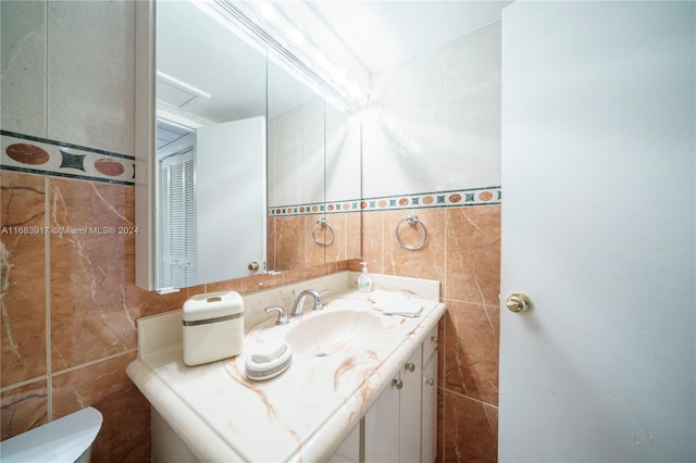 bathroom with vanity, toilet, and tile walls