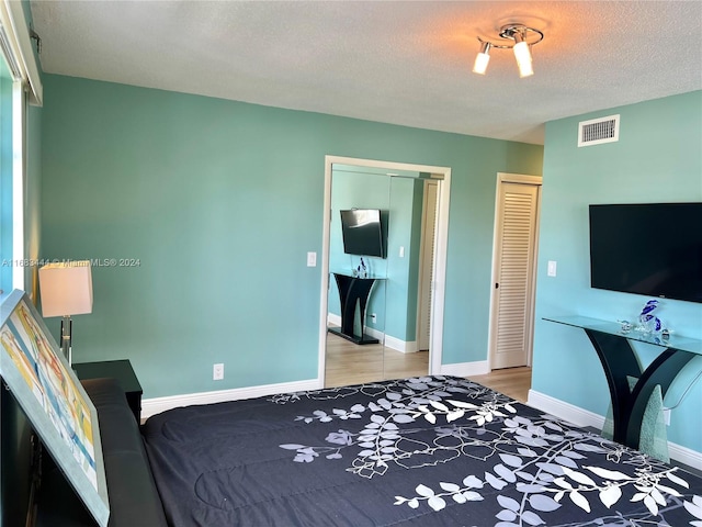 bedroom with light hardwood / wood-style floors and a textured ceiling