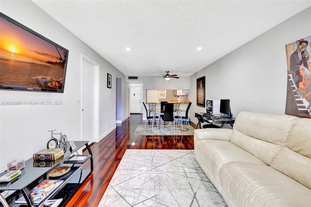 living room featuring a textured ceiling, wood-type flooring, and ceiling fan