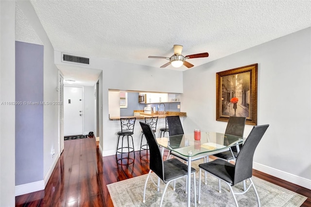 dining area featuring sink, ceiling fan, a textured ceiling, and dark hardwood / wood-style flooring