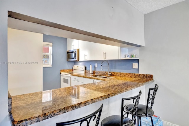 kitchen with stone countertops, white electric range, sink, white cabinets, and a textured ceiling