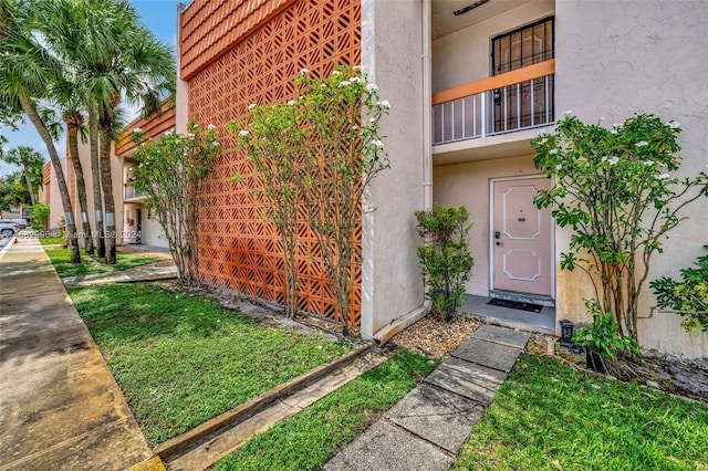 property entrance featuring a yard and a balcony