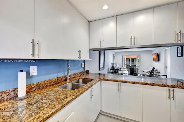 kitchen featuring stone counters, sink, white cabinetry, and kitchen peninsula