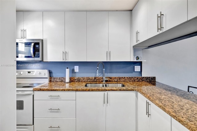 kitchen featuring dark stone countertops, white cabinets, white electric stove, and sink