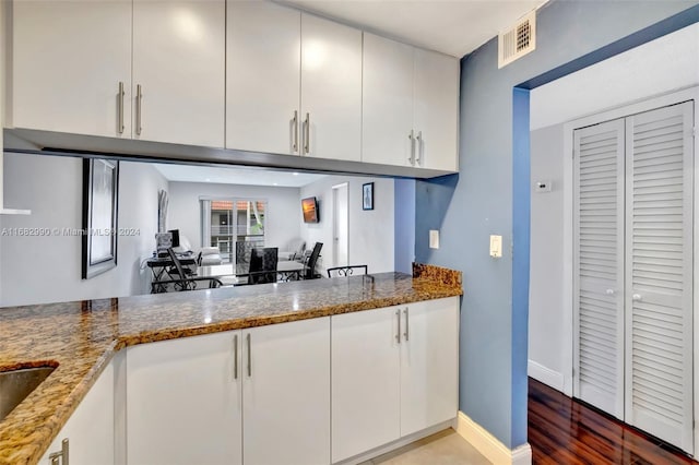 kitchen featuring white cabinetry, hardwood / wood-style flooring, and dark stone counters