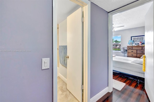 corridor with hardwood / wood-style floors and a textured ceiling