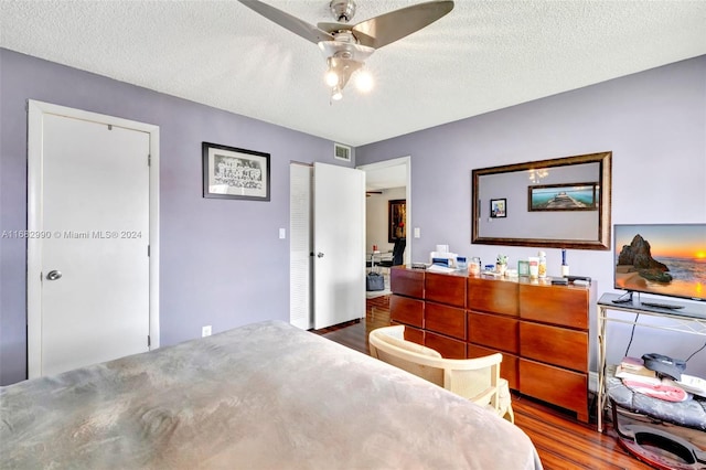 bedroom with a textured ceiling, wood-type flooring, and ceiling fan