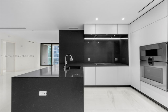 kitchen with dark countertops, white cabinets, a sink, modern cabinets, and stovetop