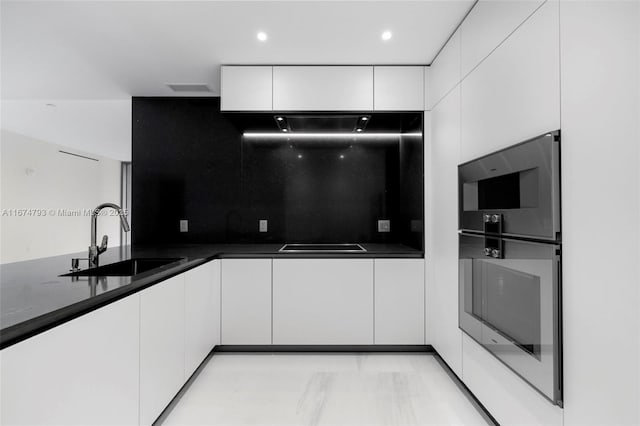 kitchen with recessed lighting, decorative backsplash, white cabinetry, a sink, and dark stone countertops