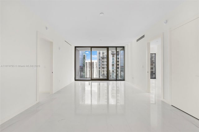 spare room featuring marble finish floor and floor to ceiling windows