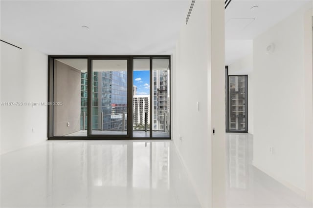 unfurnished room featuring a wall of windows and baseboards