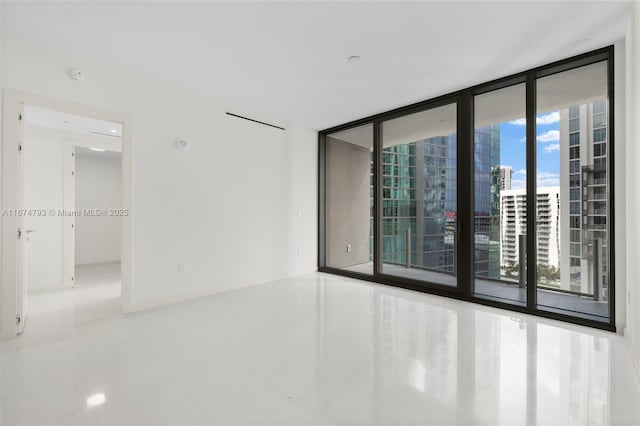 empty room with a view of city, floor to ceiling windows, and baseboards