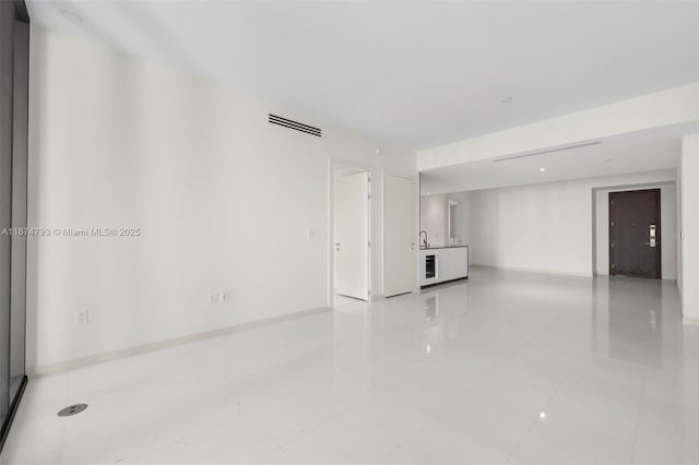 unfurnished room featuring visible vents, baseboards, and a sink