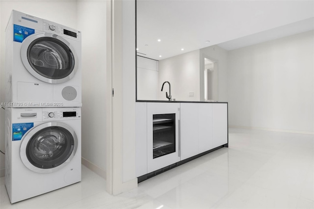 clothes washing area with laundry area, stacked washer / dryer, a sink, and recessed lighting