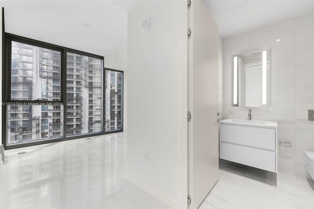 bathroom with vanity, toilet, and tile walls