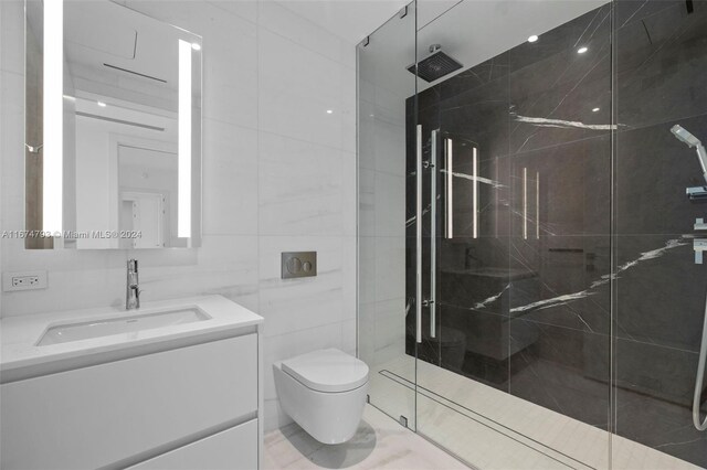 bathroom featuring tile walls, vanity, a shower with shower door, and toilet