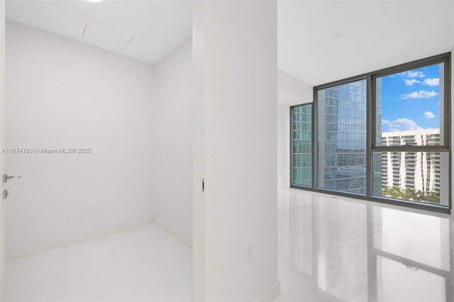 tiled empty room featuring floor to ceiling windows