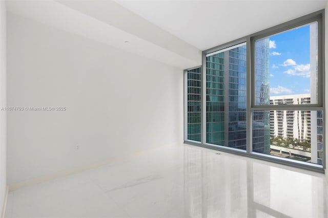 spare room featuring expansive windows and baseboards