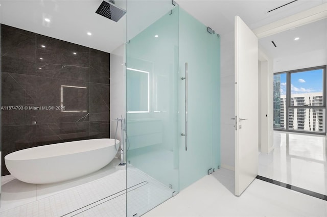 full bath featuring a freestanding bath, a shower stall, tile walls, and recessed lighting