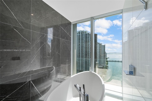 bathroom with expansive windows, a water view, and a washtub