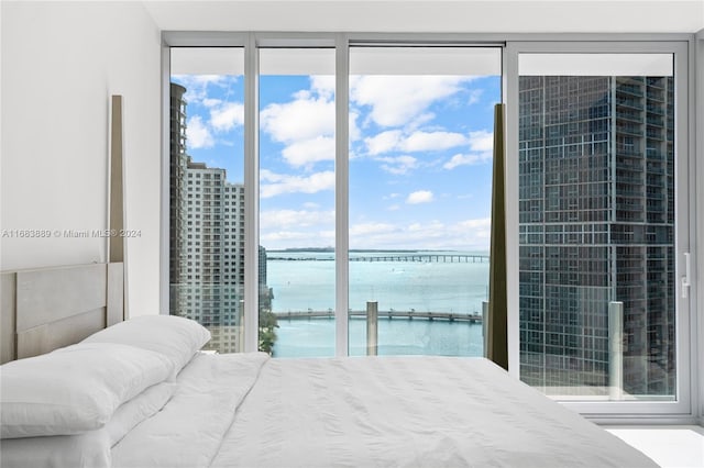 bedroom with a water view and a wall of windows