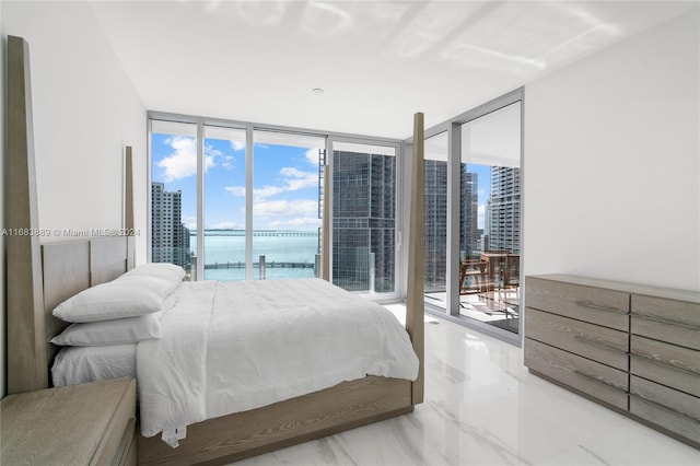 bedroom featuring a water view, multiple windows, access to exterior, and floor to ceiling windows