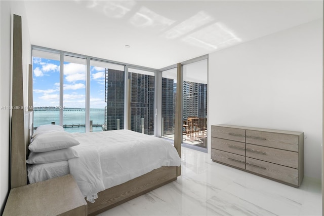 bedroom with a wall of windows, multiple windows, a water view, and access to exterior