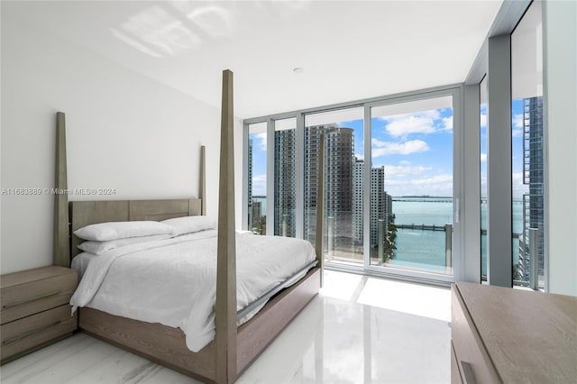 bedroom featuring floor to ceiling windows, multiple windows, light hardwood / wood-style flooring, and a water view