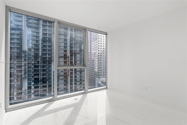 empty room featuring expansive windows and tile patterned flooring